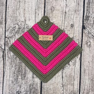 Op de afbeelding: Een groene en roze gehaakte ovenwant met een bruin label waarop "Handmade with Love" staat.