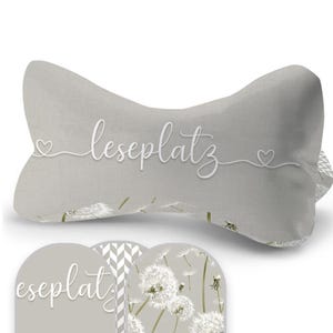 Pode incluir: Uma almofada cinzenta com o texto "leseplatz" em letras brancas. A almofada é decorada com um coração branco de cada lado do texto. A almofada está sobre um fundo branco.