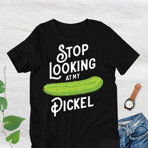 May include: Black t-shirt with white text that reads "Stop Looking At My Pickle" and a green pickle illustration.
