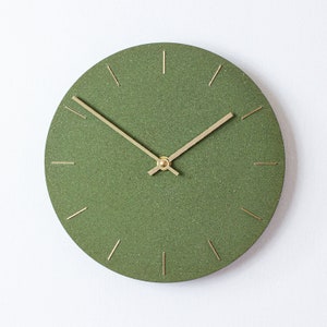 May include: A green round clock with gold hands and gold hour markers. The clock face has a textured surface.