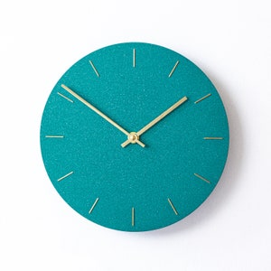Può includere: Orologio con glitter turchese con lancette dorate e indici orari dorati.