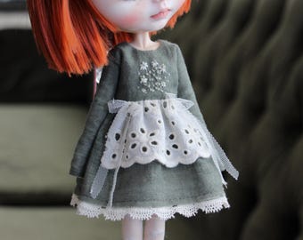 Puede incluir: Un vestido verde con ribete de encaje blanco y flores bordadas. El vestido tiene un lazo en la cintura y una falda de tul.