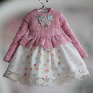 May include: A pink and white dress with a floral embroidered bodice and a white skirt with pink polka dots and a lace trim.