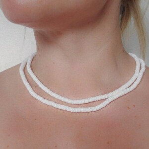 May include: A white shell necklace with two strands of small, round shells.