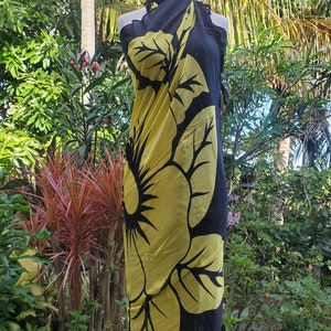 Puede incluir: Sarong negro con un gran estampado de flor de hibisco amarilla. El sarong est&aacute; drapeado sobre un maniqu&iacute;.