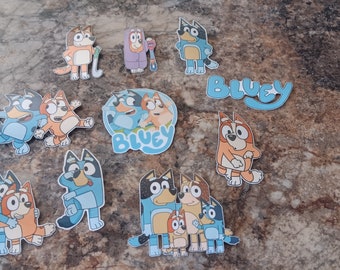 May include: A set of 10 Bluey and Bingo character stickers. The stickers feature the characters in various poses, including hugging, playing, and standing. The stickers are printed on white paper and have a glossy finish.