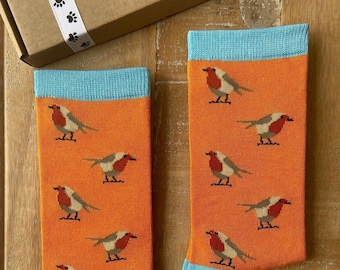 May include: A pair of orange socks with a blue trim. The socks feature a repeating pattern of robins.