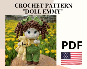 May include: Crochet pattern for a doll named "Doll Emmy" in PDF format. The doll is holding a crocheted teddy bear. The image shows the doll against a background of yellow flowers.