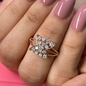 May include: A rose gold ring with a delicate design featuring a cluster of small diamonds set in a criss-cross pattern.