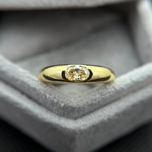 Puede incluir: Un anillo de oro con una sola piedra preciosa redonda y transparente engastada en el centro.