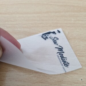 May include: A white, semi-transparent label with black text and a silhouette of a person sewing. The text reads "Sew-Modiste Creations by Dasha".
