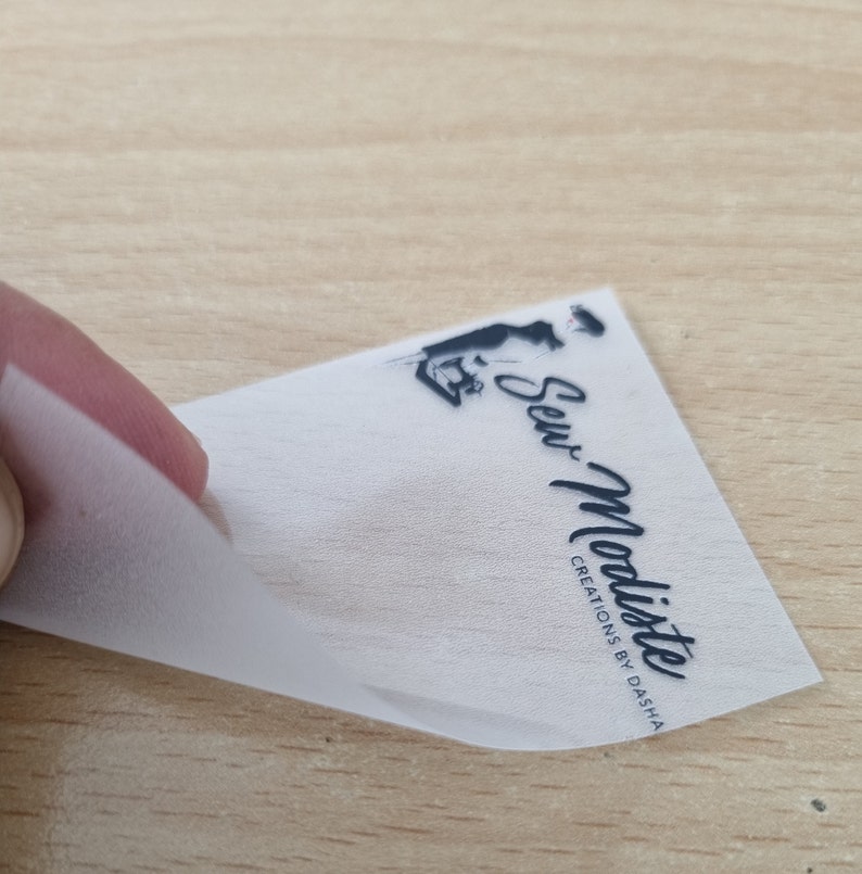 May include: A white, semi-transparent label with black text and a silhouette of a person sewing. The text reads "Sew-Modiste Creations by Dasha".