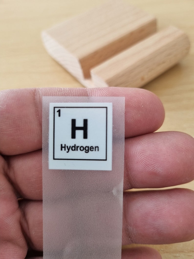 May include: A white sticker with a black border and the text "1 H Hydrogen" inside.