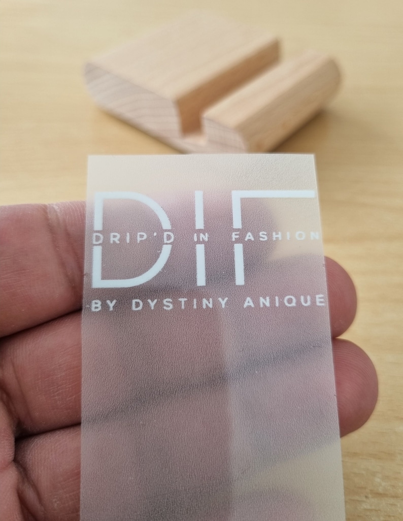 May include: A clear, frosted sticker with the text "DRIP'D IN FASHION - BY DYSTINY ANIQUE" in white lettering.