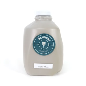 May include: A light gray paint container with a white cap. The container has a teal and white label that says "Schnubs" and "Schnub it up". A smaller label at the bottom says "Castle Moss".
