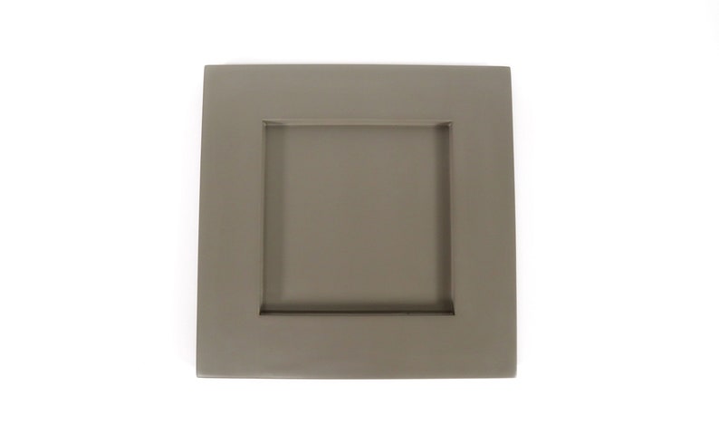May include: A square, taupe-colored cabinet door with a recessed square panel. The door is a solid color and has a simple, modern design. The cabinet door is likely for a kitchen or bathroom.