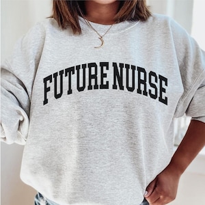 May include: A gray sweatshirt with the text "FUTURE NURSE" printed in black in an arched font.