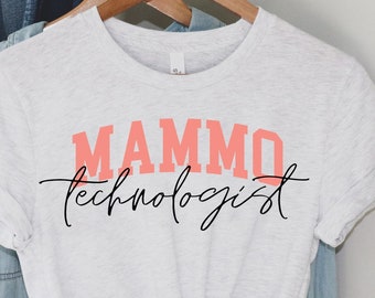 Puede incluir: Una camiseta blanca con el texto "MAMMO technologist" en letras rosas y negras.