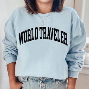 May include: A light blue sweatshirt with the text "WORLD TRAVELER" printed in black.