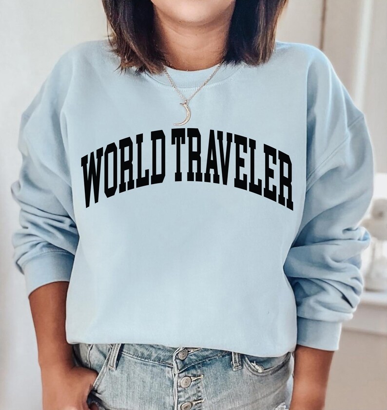 May include: A light blue sweatshirt with the text "WORLD TRAVELER" printed in black.