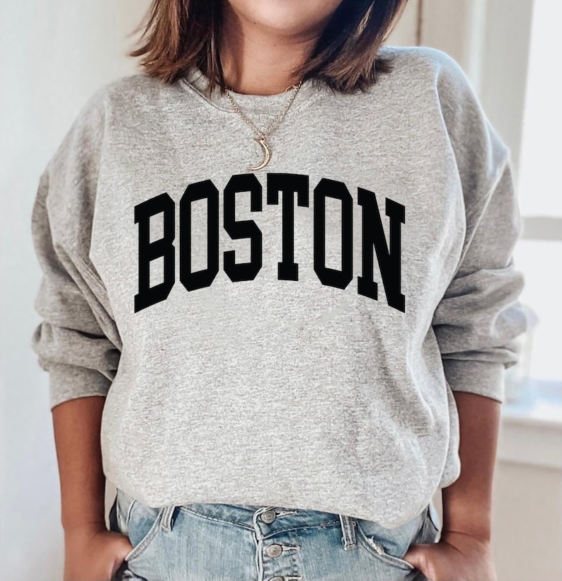 K&ouml;nnte beinhalten: Grauer Pullover mit schwarzem Text, der "BOSTON" in einer College-Schriftart lautet.