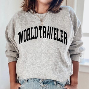 May include: A gray sweatshirt with the text "WORLD TRAVELER" printed in black.