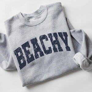 May include: Gray sweatshirt with a navy blue distressed graphic that says "Beachy".