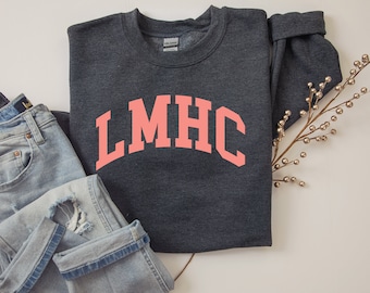 May include: A dark gray sweatshirt with a pink arch design that reads "LMHC".