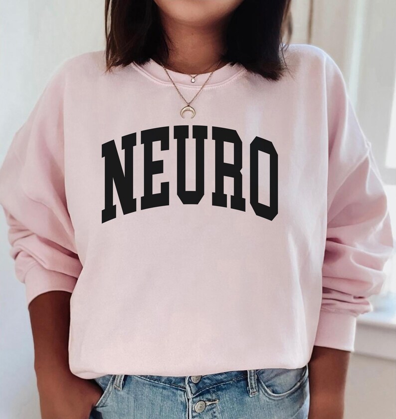 K&ouml;nnte beinhalten: Ein rosa Sweatshirt mit dem Wort "NEURO" in schwarzen Blockbuchstaben.