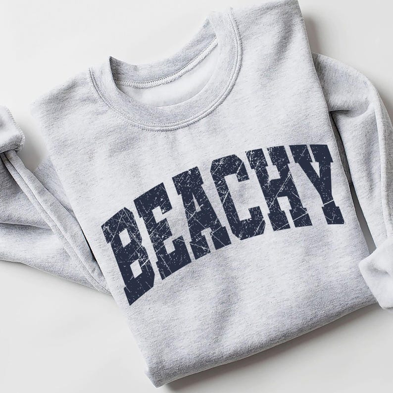 May include: A gray sweatshirt with a navy blue distressed graphic that says "Beachy" in a large, bold font.