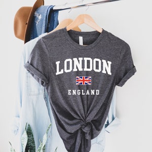 May include: A dark gray t-shirt with white text that says "LONDON ENGLAND" and a small Union Jack flag.