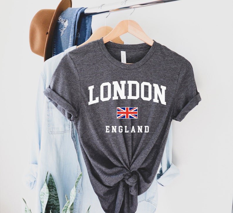 May include: A dark gray t-shirt with white text that says "LONDON ENGLAND" and a small Union Jack flag.