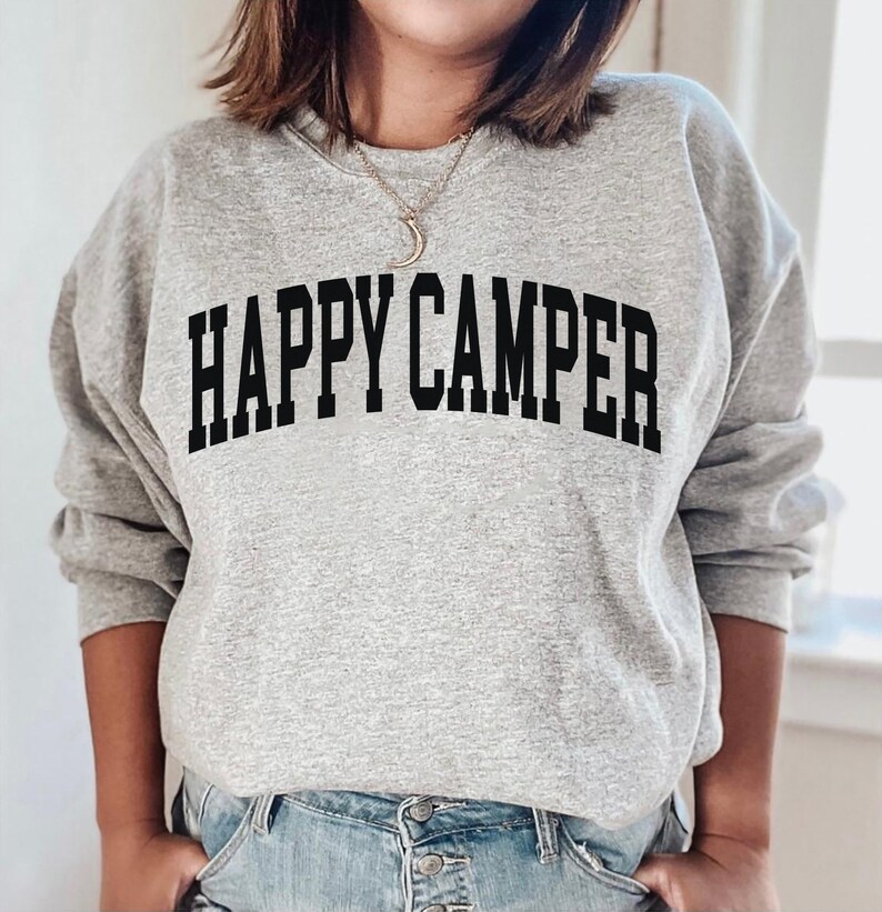 Peut inclure: Un sweat-shirt gris avec le texte "HAPPY CAMPER" imprim&eacute; en noir.