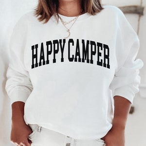 Peut inclure: Sweat-shirt blanc avec un texte noir qui dit "HAPPY CAMPER" dans une police d'&eacute;criture universitaire.