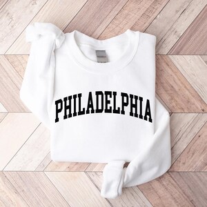 May include: White sweatshirt with black text that reads "PHILADELPHIA" in an arched font.