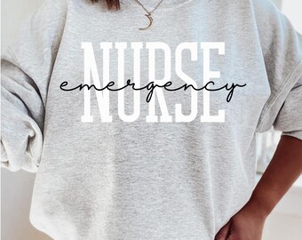 Op de afbeelding: Een lichtgrijs sweatshirt met de witte tekst "NURSE emergency NURSE". Het woord "emergency" is in cursief geschreven. De sweatshirt heeft lange mouwen en een ronde hals.
