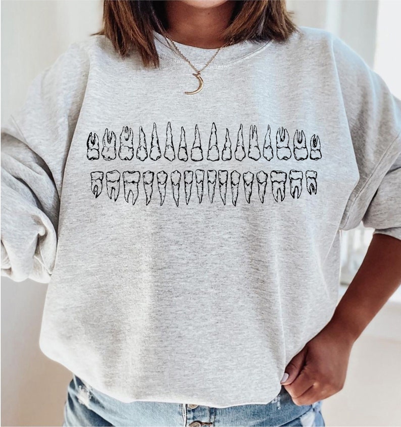 May include: A gray sweatshirt with a black graphic of a full set of teeth. The graphic is centered on the sweatshirt.