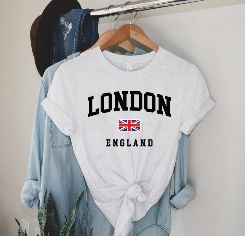 May include: A white t-shirt with a black graphic that says "LONDON" with the Union Jack flag and "ENGLAND" underneath.