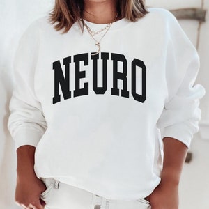 K&ouml;nnte beinhalten: Wei&szlig;er Pullover mit schwarzem Text, der "NEURO" in einer College-Schriftart lautet.