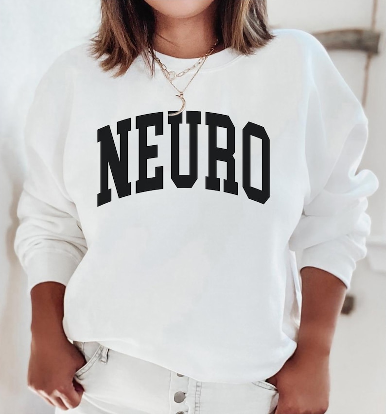 K&ouml;nnte beinhalten: Wei&szlig;er Pullover mit schwarzem Text, der "NEURO" in einer College-Schriftart lautet.
