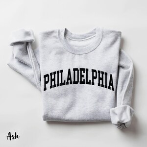 May include: Ash grey sweatshirt with the text "PHILADELPHIA" printed in black across the front.
