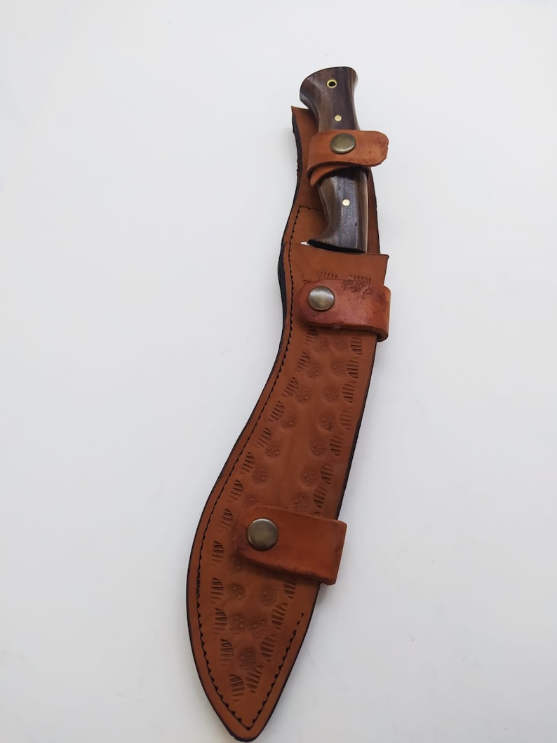 May include: A brown leather sheath with a decorative pattern and a brass snap closure. A wooden-handled knife is inside the sheath.