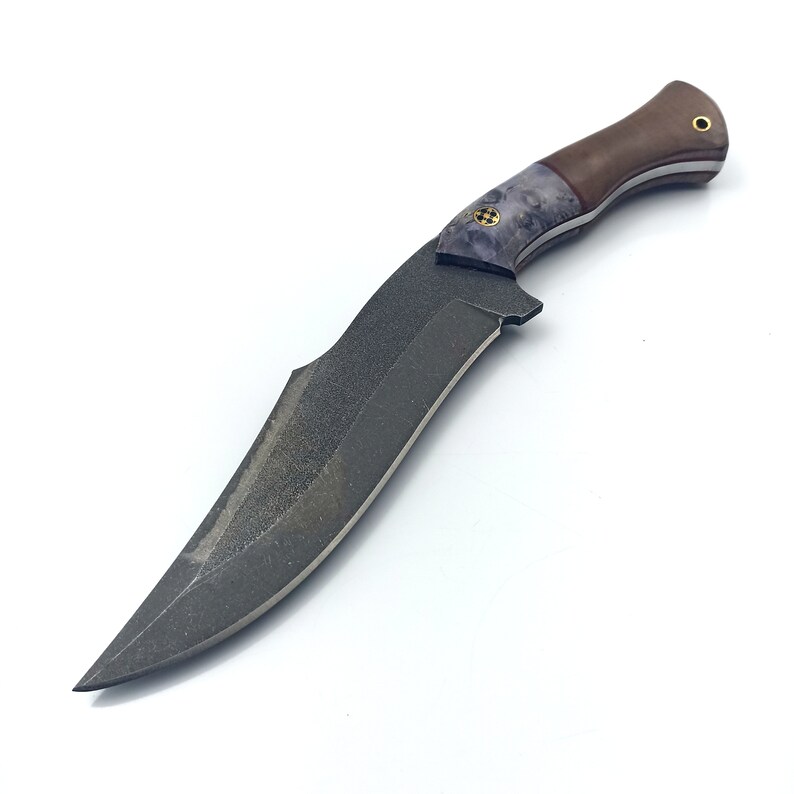 May include: A black and grey knife with a brown and purple handle. The blade has a textured finish and the handle has a unique pattern.