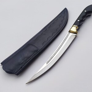 May include: A black leather sheath with a silver blade knife with a black handle and gold accents.
