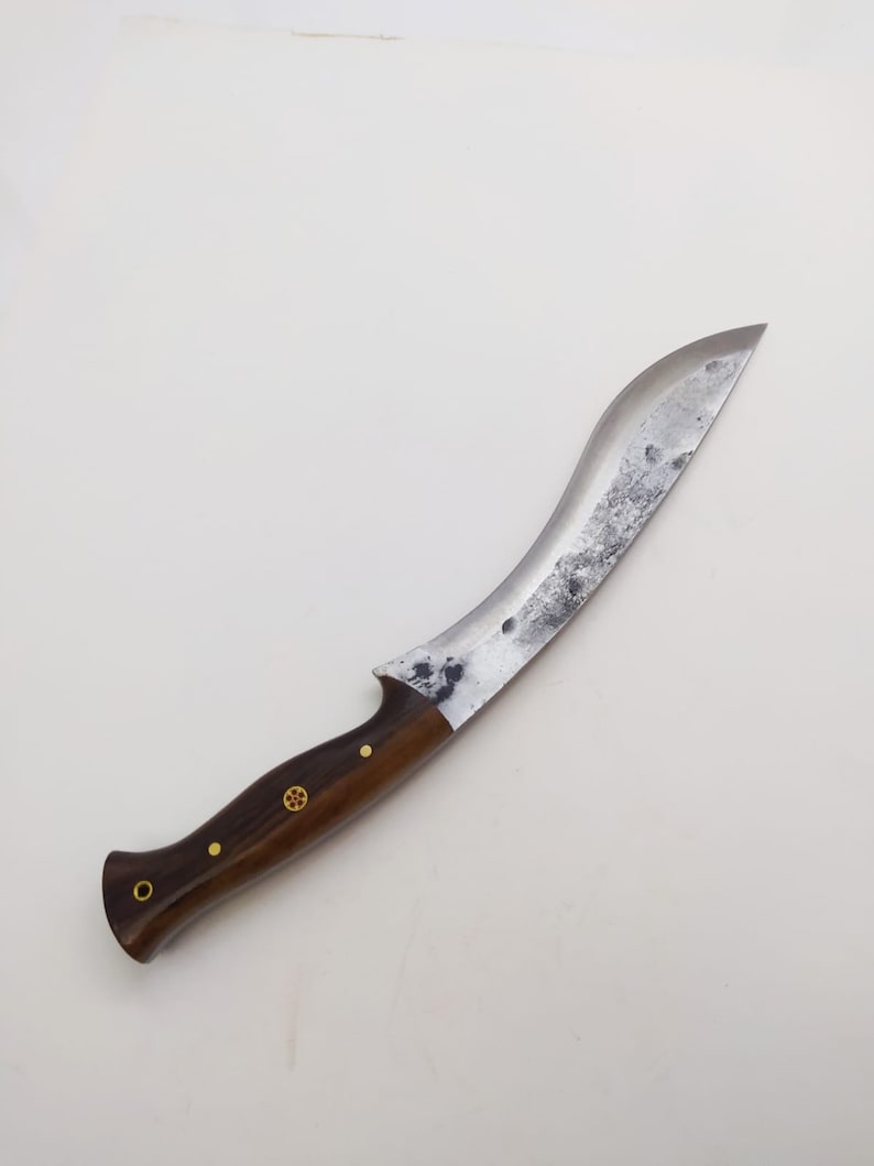 May include: A curved, silver-colored knife with a dark brown wooden handle. The handle has brass accents.