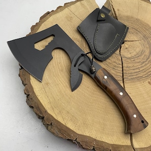 May include: A black axe with a wooden handle and a leather sheath. The axe has a small hole in the blade and a small knife attached to the handle.