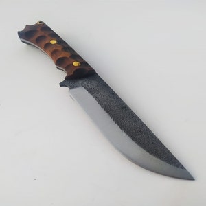 Puede incluir: Un cuchillo artesanal con mango de madera marrón y hoja de metal gris. La hoja tiene un acabado texturizado.