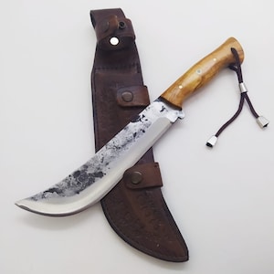 May include: A curved, silver knife with a wooden handle and a brown leather sheath. The sheath has a decorative design and a snap closure.