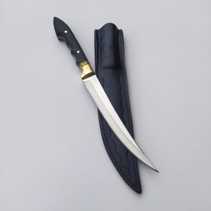 May include: A black-handled knife with a gold accent and a silver blade. The knife is in a black leather sheath.