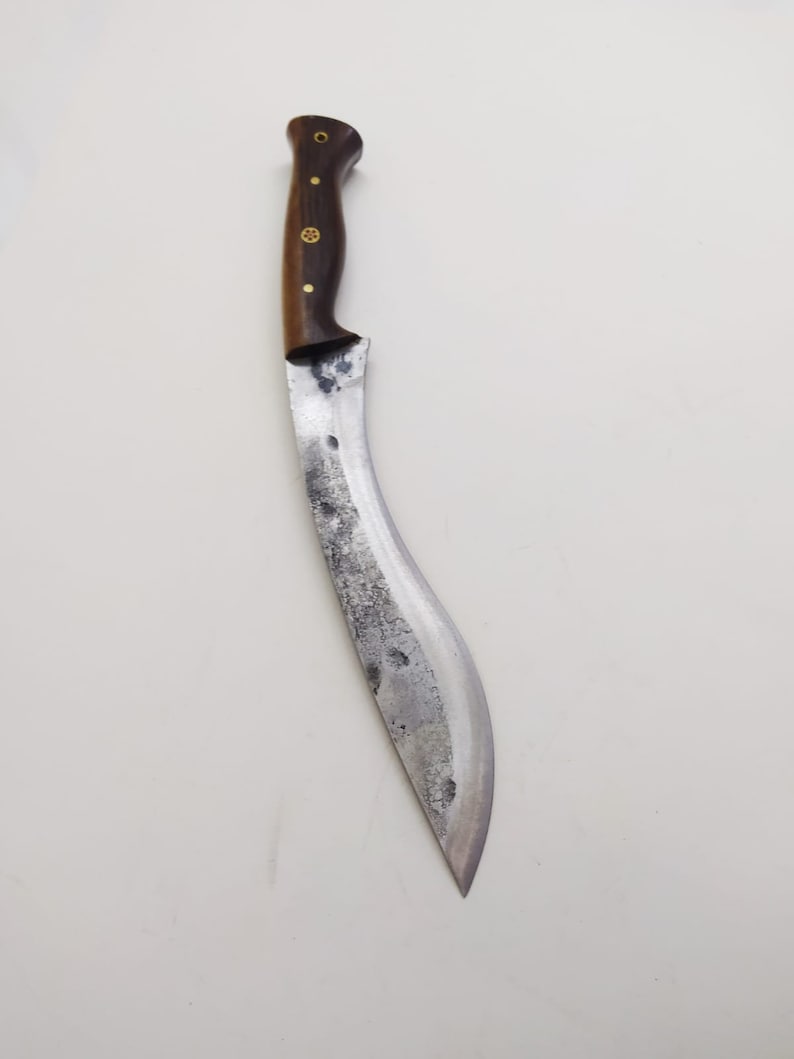 May include: A curved, silver-colored knife with a wooden handle. The handle has a dark brown color and gold accents.